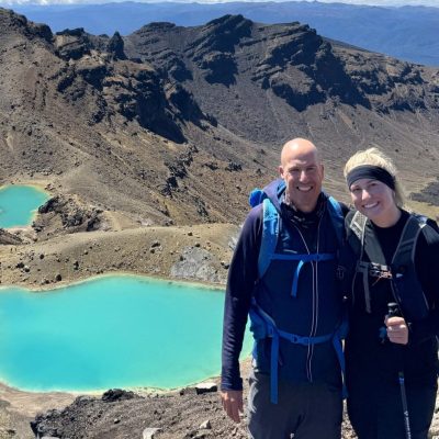 Georgia and her dad, standing in front of turquoise lake at the top of mountain in New Zealand.